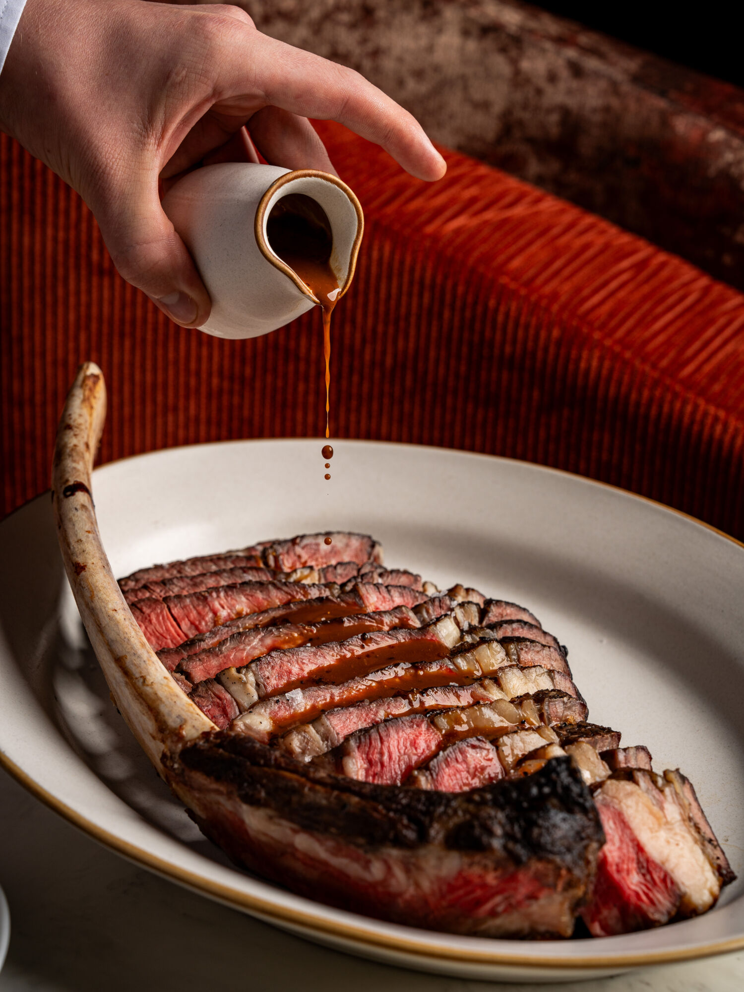 Sauce being poured on a steak